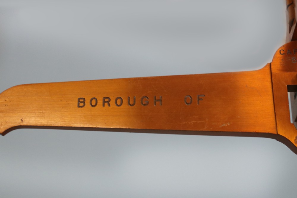 A large hanging brass beam balance scale featuring stamped lettering, suspended chain links, and two circular brass pans. View VIII