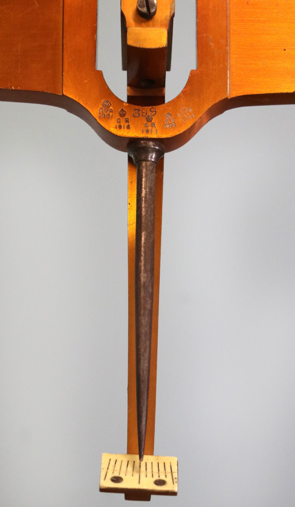 A large hanging brass beam balance scale featuring stamped lettering, suspended chain links, and two circular brass pans. View XII