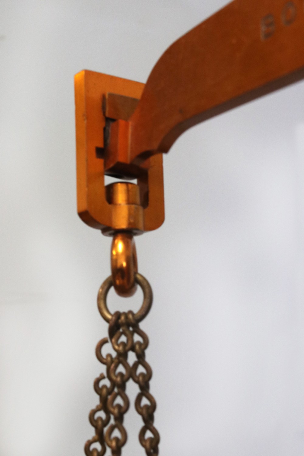 A large hanging brass beam balance scale featuring stamped lettering, suspended chain links, and two circular brass pans. View XVII