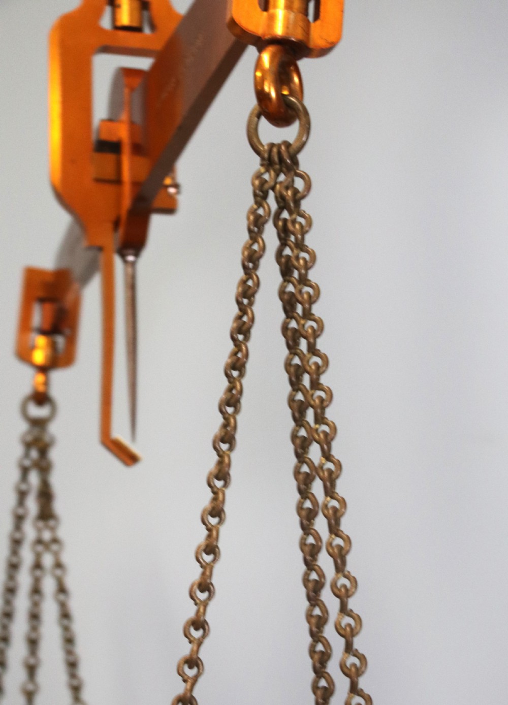 A large hanging brass beam balance scale featuring stamped lettering, suspended chain links, and two circular brass pans. View XVIII