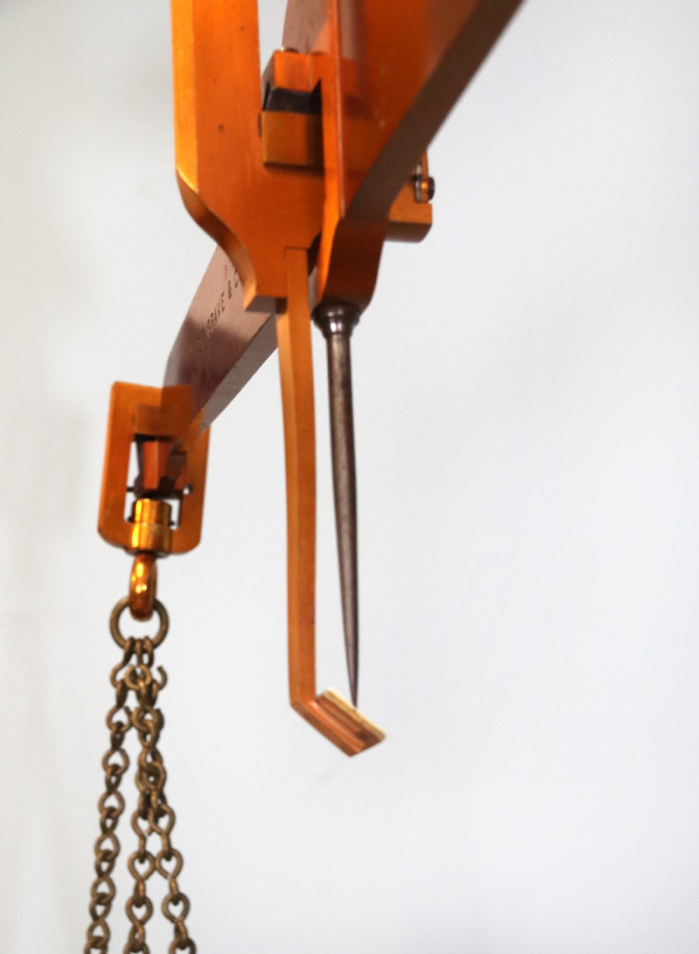 A large hanging brass beam balance scale featuring stamped lettering, suspended chain links, and two circular brass pans. View XX