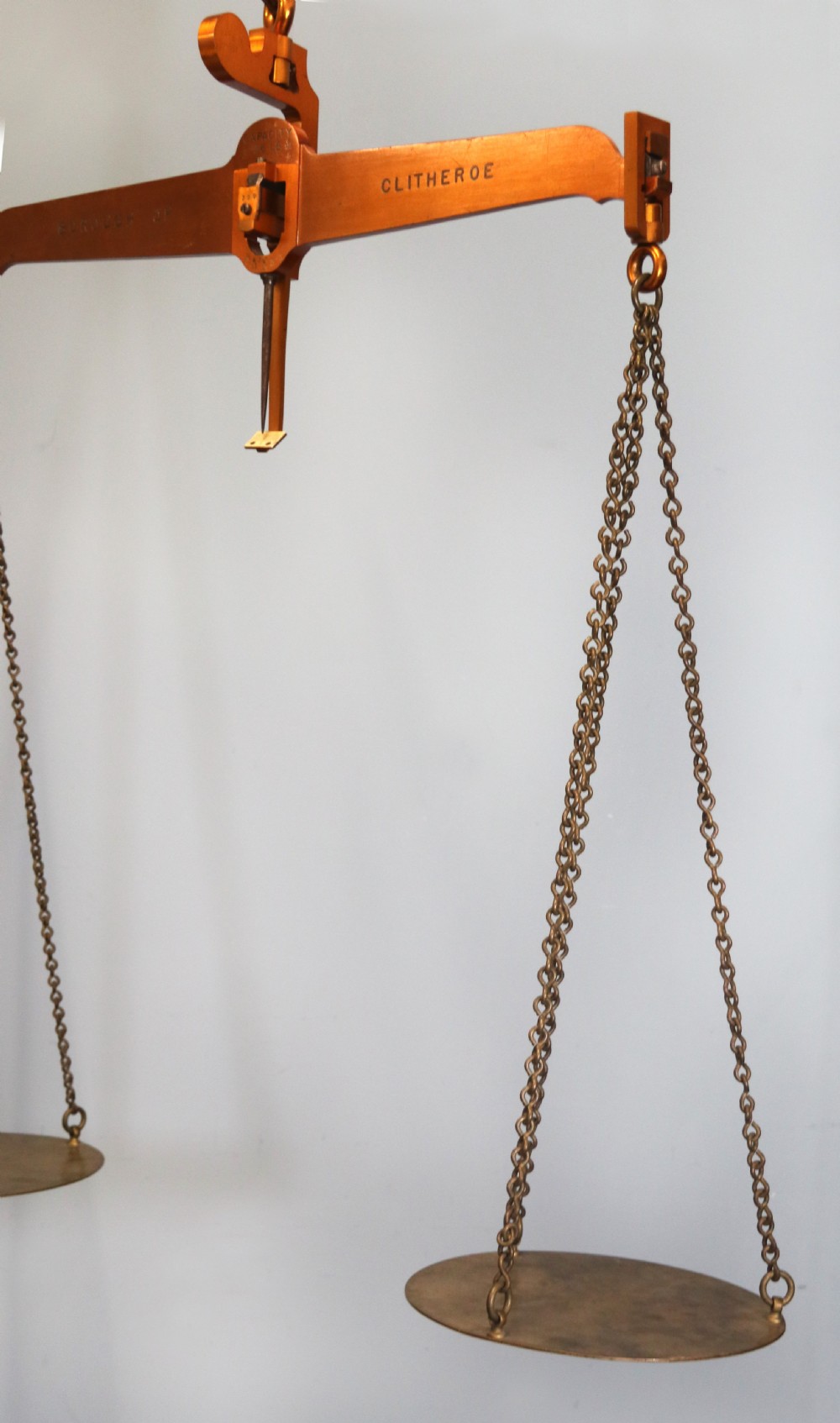 A large hanging brass beam balance scale featuring stamped lettering, suspended chain links, and two circular brass pans. View XXII