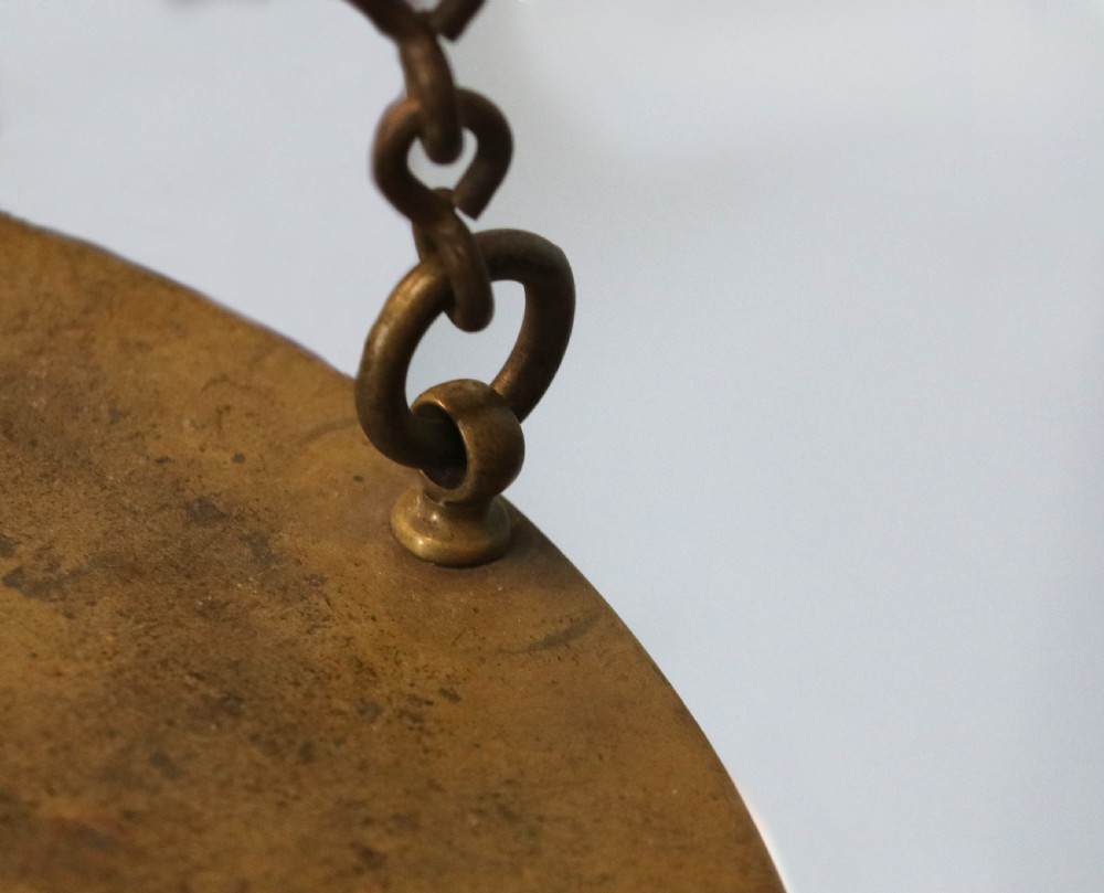 A large hanging brass beam balance scale featuring stamped lettering, suspended chain links, and two circular brass pans. View XXVII