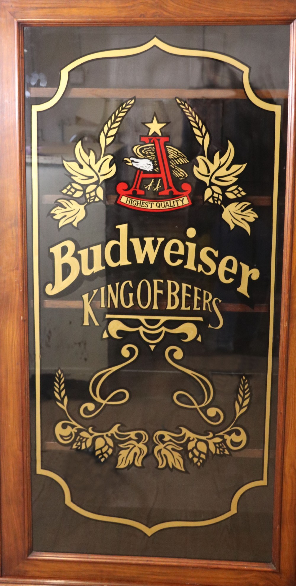 An early 20th-century walnut glazed display cabinet featuring two glass doors with gilded Budweiser advertising signwriting and cabriole legs. View IV