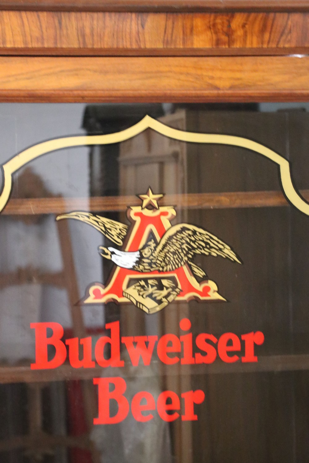 An early 20th-century walnut glazed display cabinet featuring two glass doors with gilded Budweiser advertising signwriting and cabriole legs. View VIII