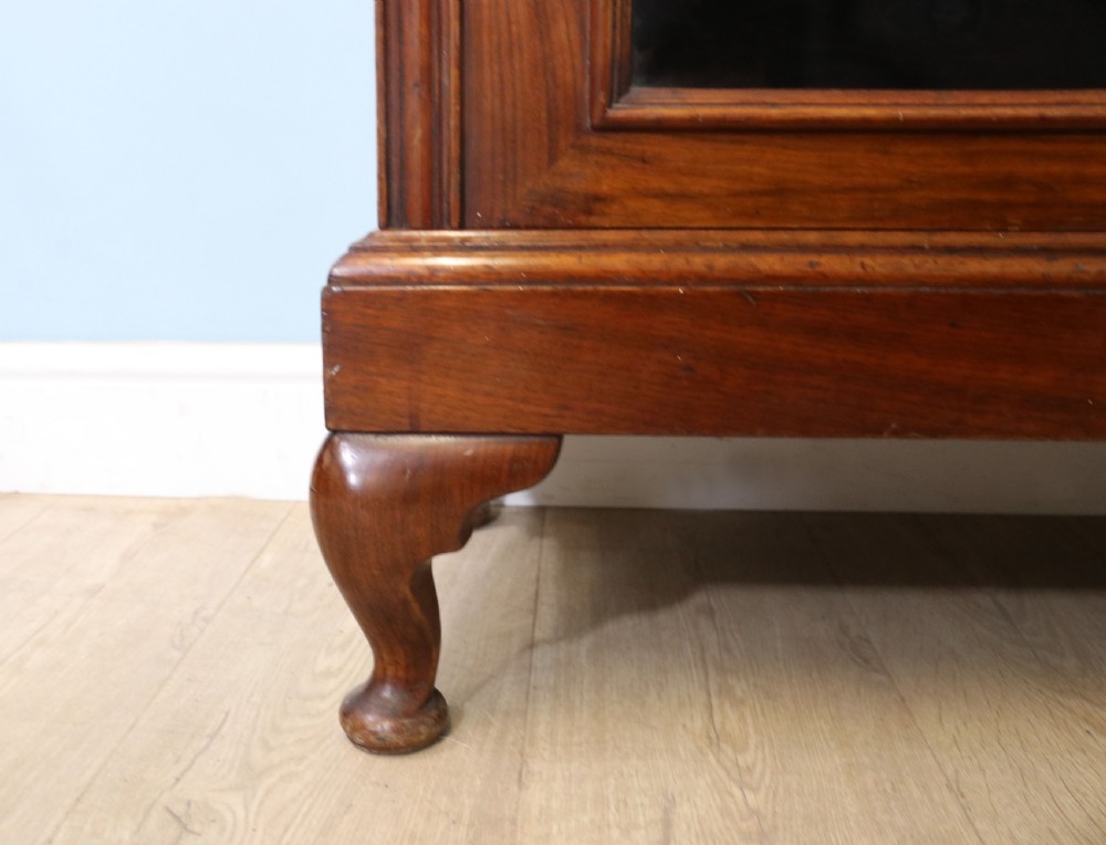An early 20th-century walnut glazed display cabinet featuring two glass doors with gilded Budweiser advertising signwriting and cabriole legs. View XII