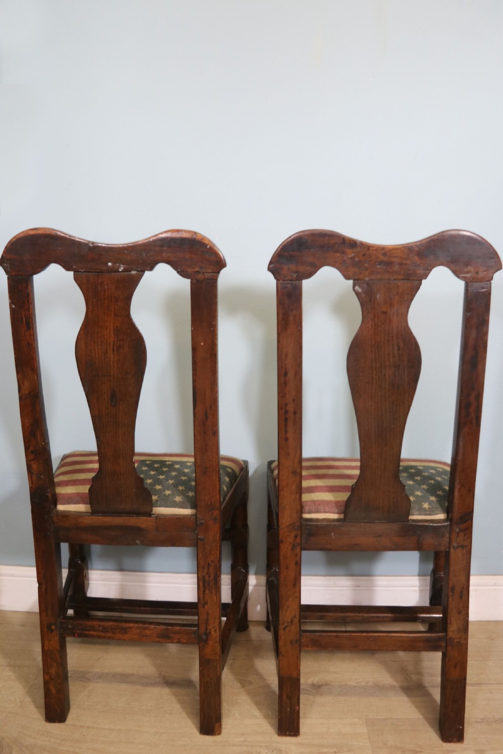 A pair of dark oak side chairs featuring vasiform back splats, turned front stretchers, and seats upholstered in an American flag pattern fabric. View V