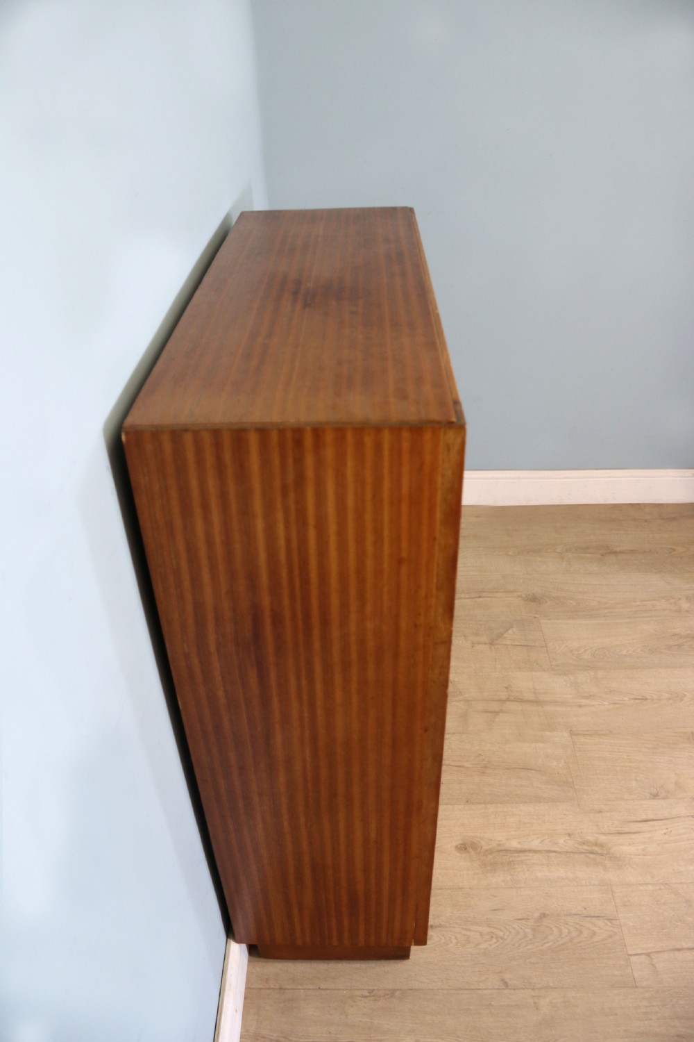 A 1930s light mahogany two-door glazed bookcase featuring white lettering on glass panels set over an enclosed wooden base. View V