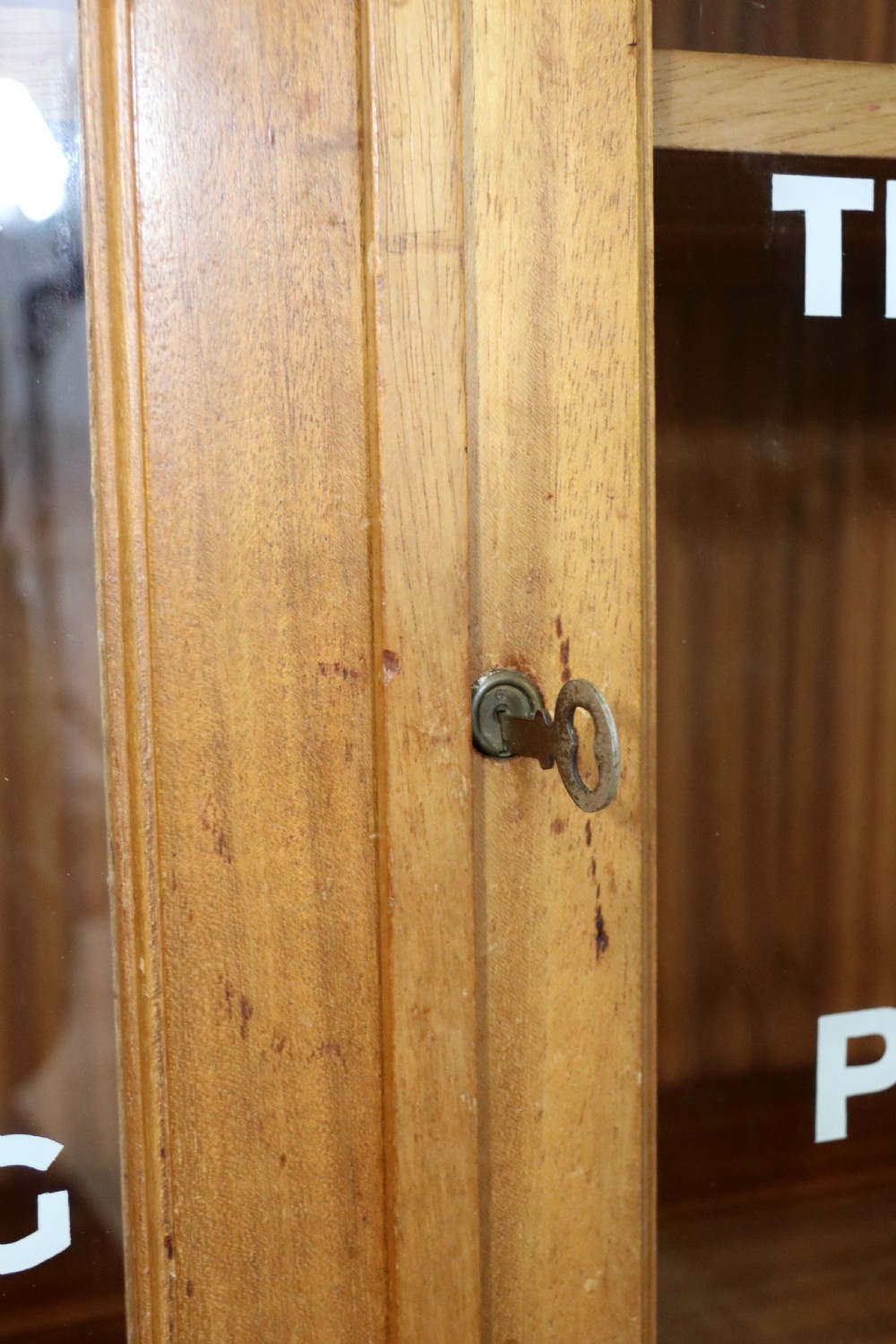 A 1930s light mahogany two-door glazed bookcase featuring white lettering on glass panels set over an enclosed wooden base. View XII