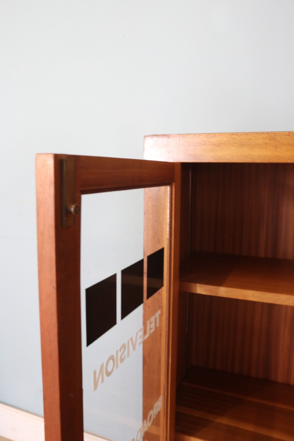 A 1930s light mahogany two-door glazed bookcase featuring white lettering on glass panels set over an enclosed wooden base. View XIII