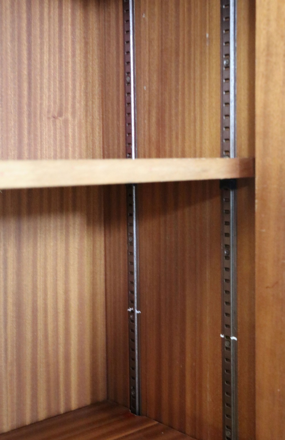 A 1930s light mahogany two-door glazed bookcase featuring white lettering on glass panels set over an enclosed wooden base. View XV