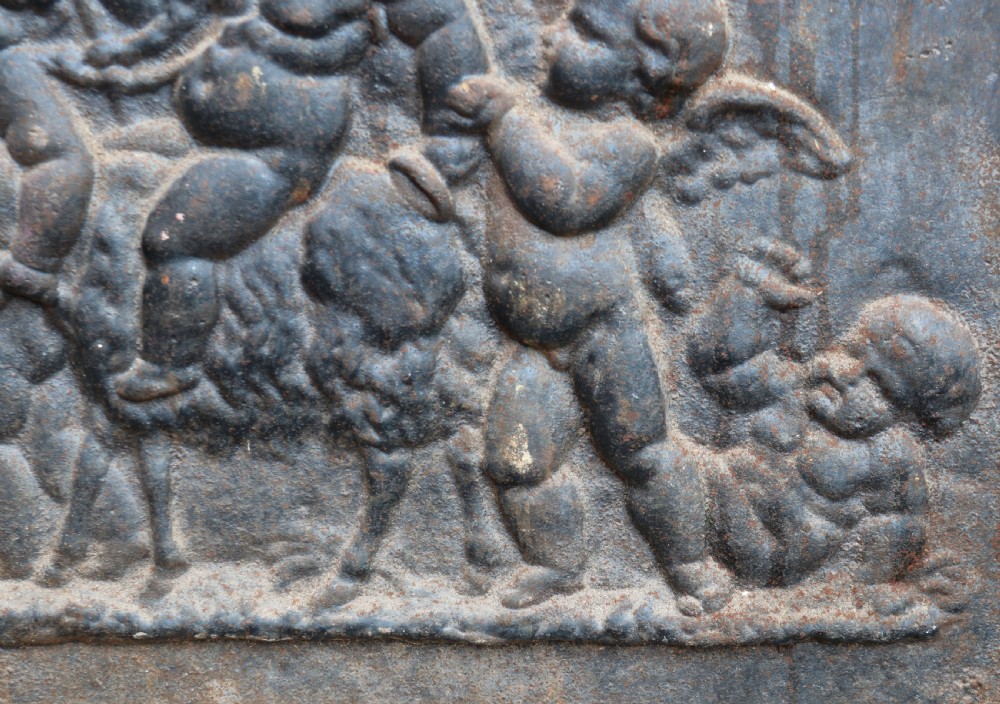 A square cast iron fireback featuring a raised relief scene of cherubs and putti beneath a leafy tree surrounded by a moulded border. View VII