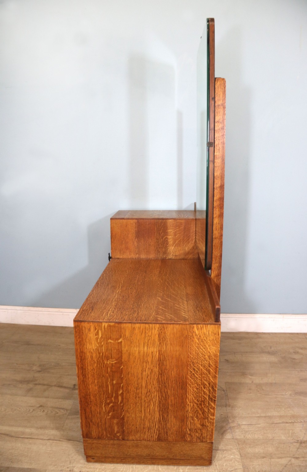 An asymmetrical golden oak dressing chest with a left-hand side cupboard, two drawers on the right, metal handles, and an off-centre tall mirror. View V