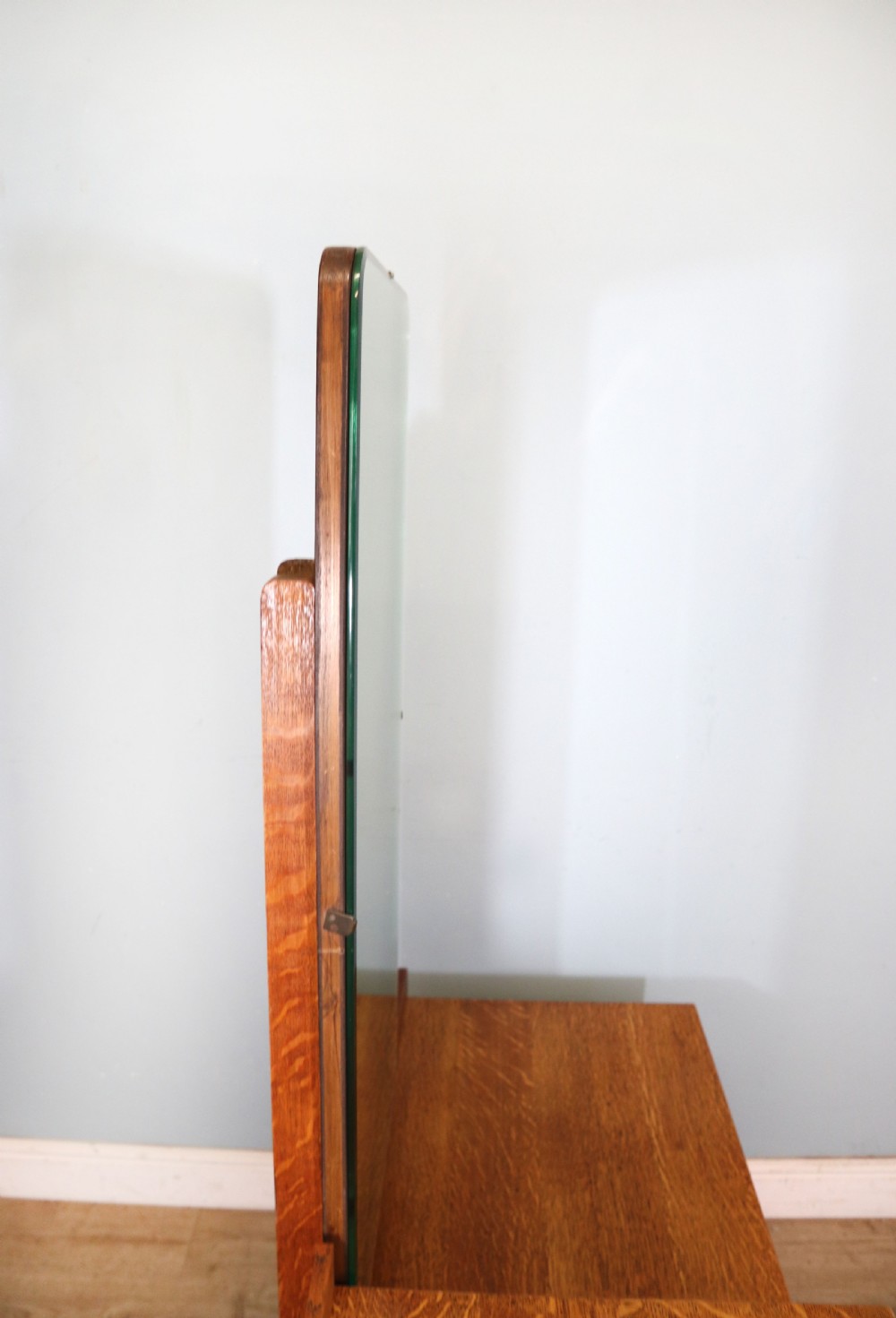An asymmetrical golden oak dressing chest with a left-hand side cupboard, two drawers on the right, metal handles, and an off-centre tall mirror. View X