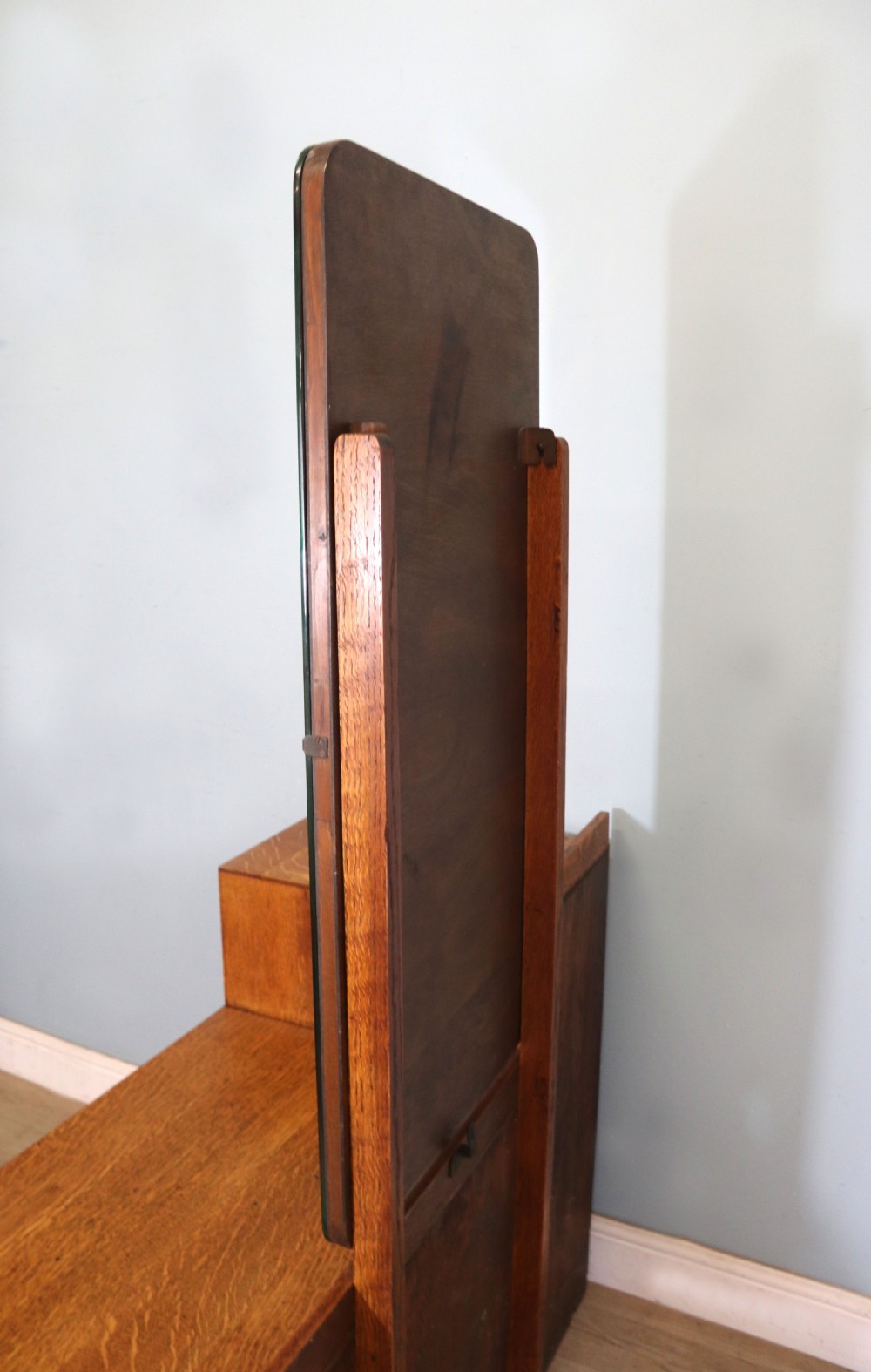 An asymmetrical golden oak dressing chest with a left-hand side cupboard, two drawers on the right, metal handles, and an off-centre tall mirror. View XIV
