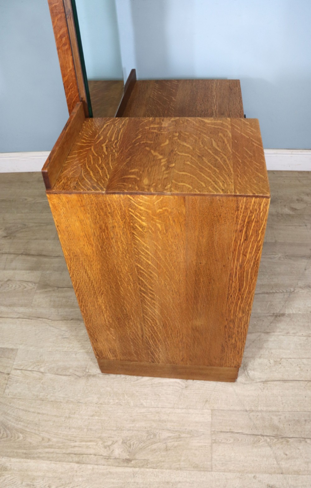 An asymmetrical golden oak dressing chest with a left-hand side cupboard, two drawers on the right, metal handles, and an off-centre tall mirror. View XVIII