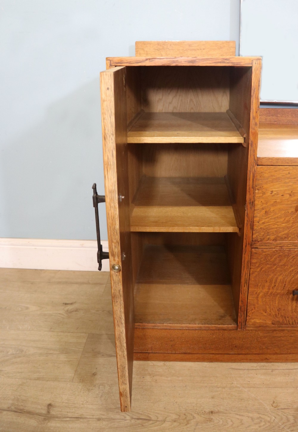An asymmetrical golden oak dressing chest with a left-hand side cupboard, two drawers on the right, metal handles, and an off-centre tall mirror. View XX