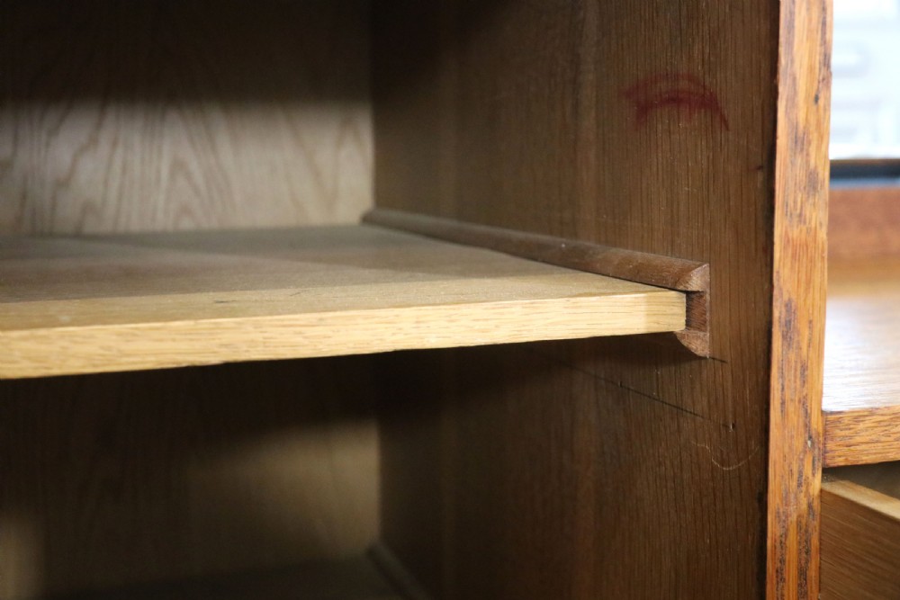 An asymmetrical golden oak dressing chest with a left-hand side cupboard, two drawers on the right, metal handles, and an off-centre tall mirror. View XXV