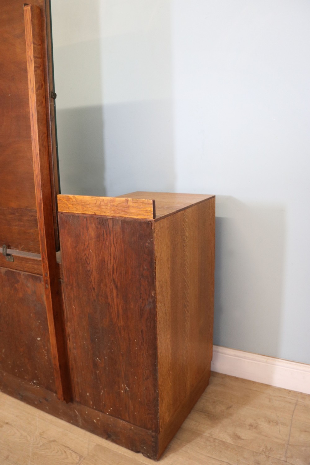 An asymmetrical golden oak dressing chest with a left-hand side cupboard, two drawers on the right, metal handles, and an off-centre tall mirror. View XXVIII