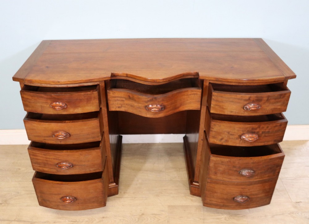 A late Victorian mahogany twin pedestal desk featuring a curved front structure and nine drawers with turned wooden handles. View III