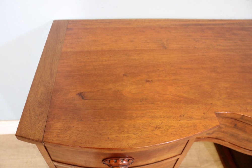 A late Victorian mahogany twin pedestal desk featuring a curved front structure and nine drawers with turned wooden handles. View VIII