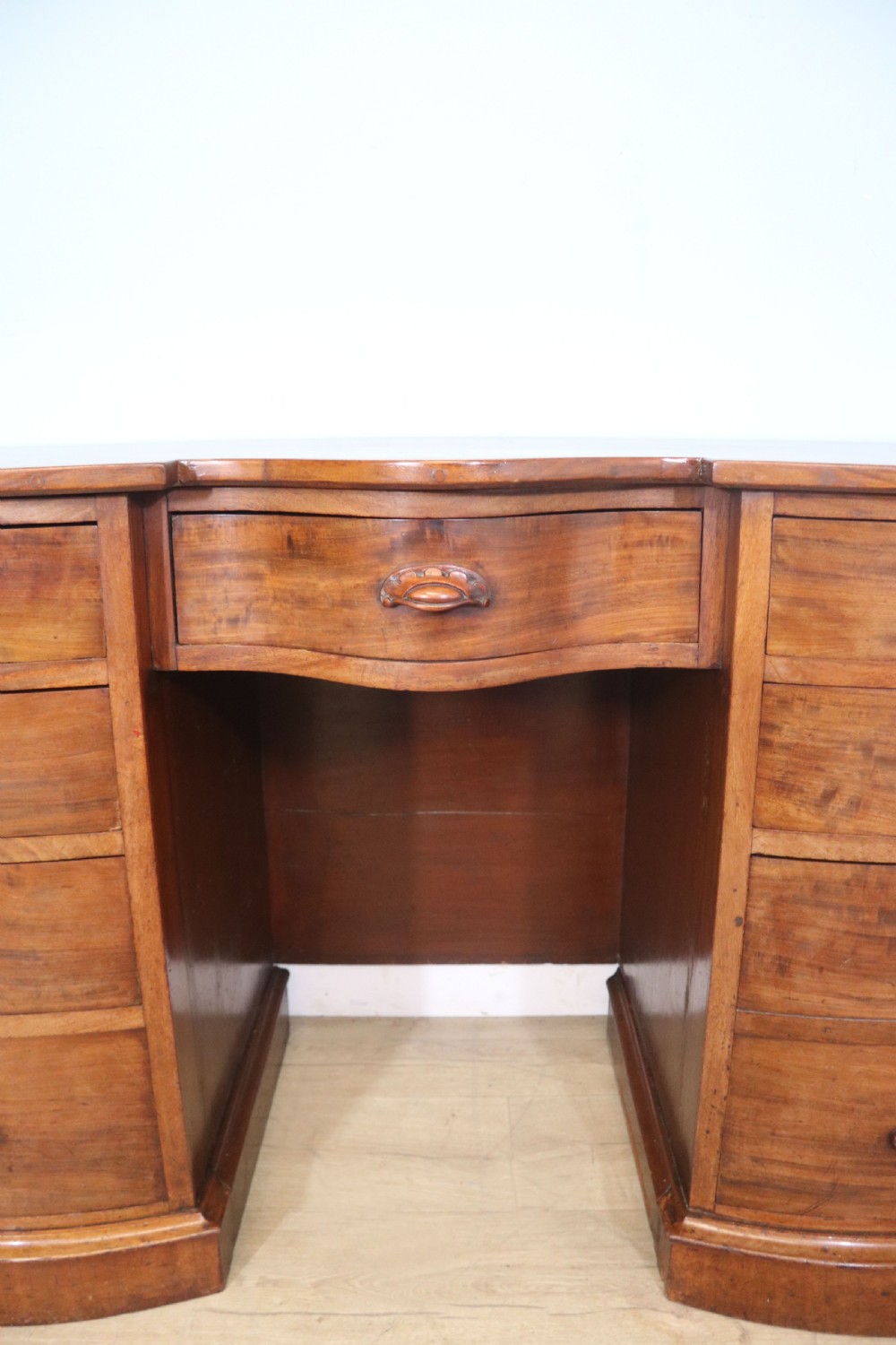 A late Victorian mahogany twin pedestal desk featuring a curved front structure and nine drawers with turned wooden handles. View XI