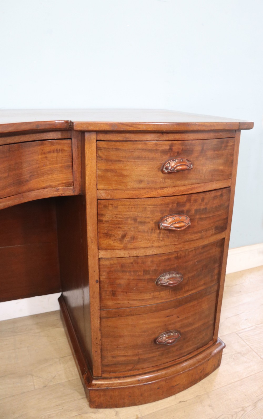 A late Victorian mahogany twin pedestal desk featuring a curved front structure and nine drawers with turned wooden handles. View XII