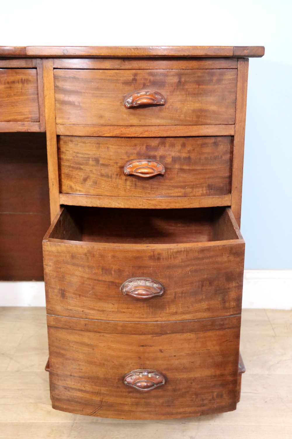 A late Victorian mahogany twin pedestal desk featuring a curved front structure and nine drawers with turned wooden handles. View XIII