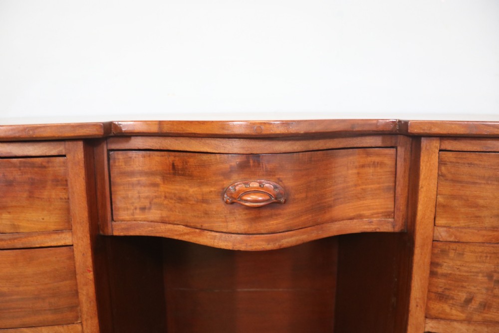 A late Victorian mahogany twin pedestal desk featuring a curved front structure and nine drawers with turned wooden handles. View XIV