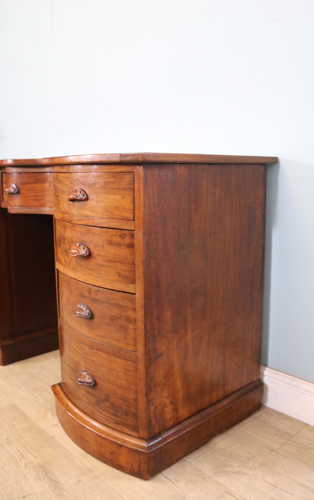 A late Victorian mahogany twin pedestal desk featuring a curved front structure and nine drawers with turned wooden handles. View XV