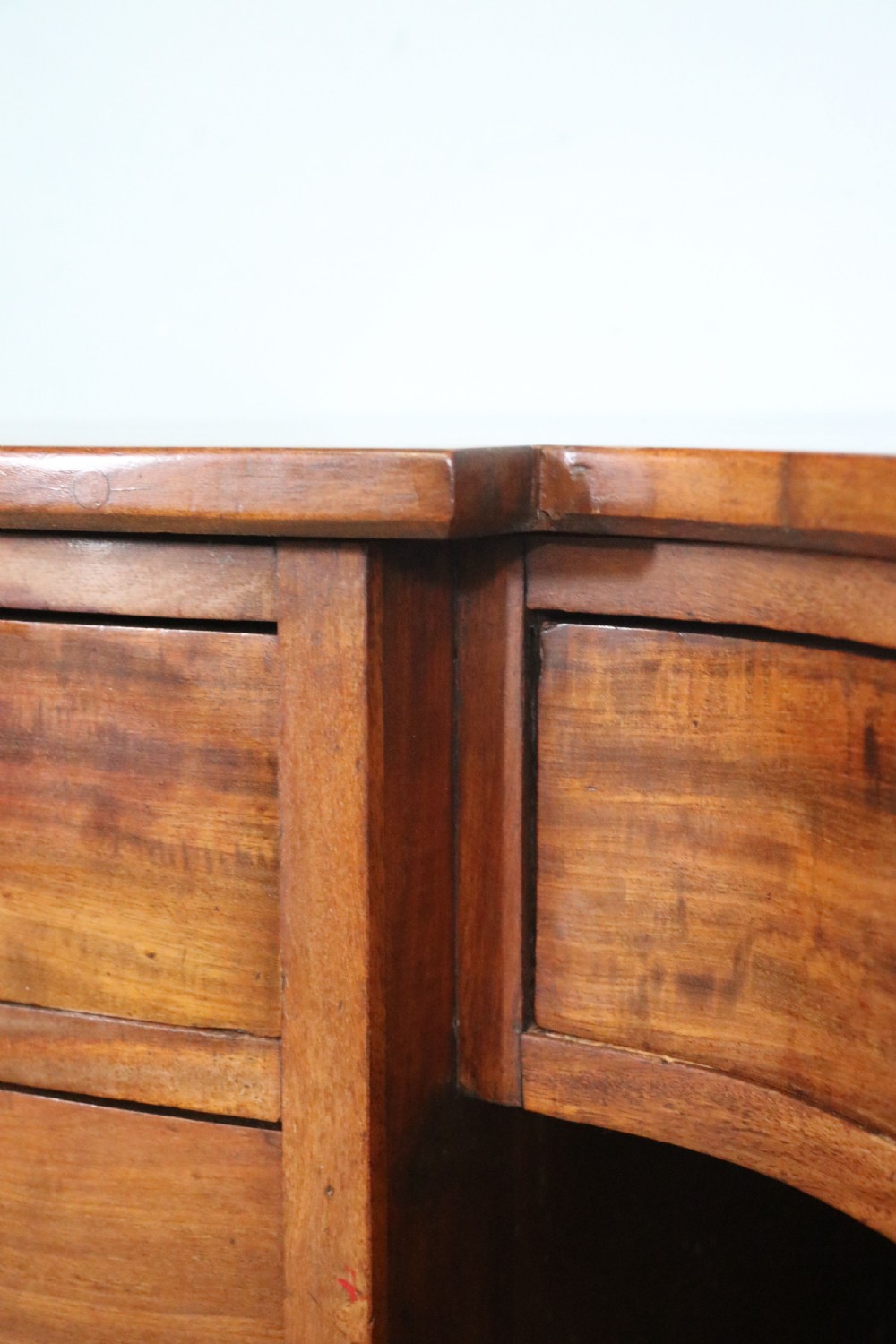 A late Victorian mahogany twin pedestal desk featuring a curved front structure and nine drawers with turned wooden handles. View XVII