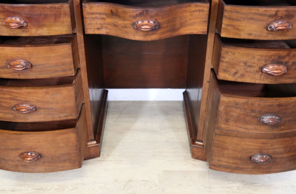 A late Victorian mahogany twin pedestal desk featuring a curved front structure and nine drawers with turned wooden handles. View XVIII