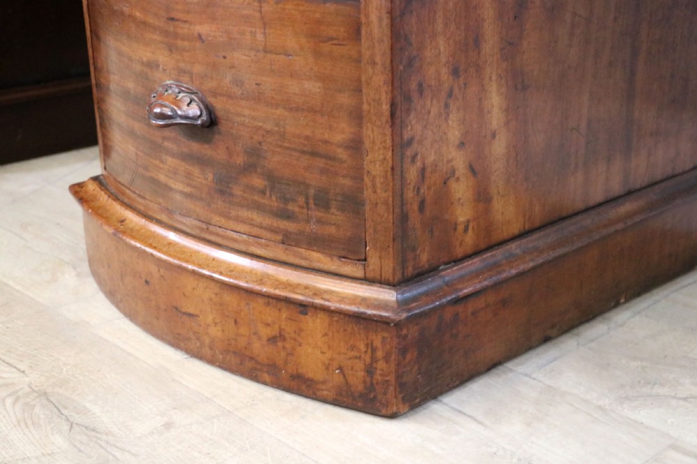 A late Victorian mahogany twin pedestal desk featuring a curved front structure and nine drawers with turned wooden handles. View XXI