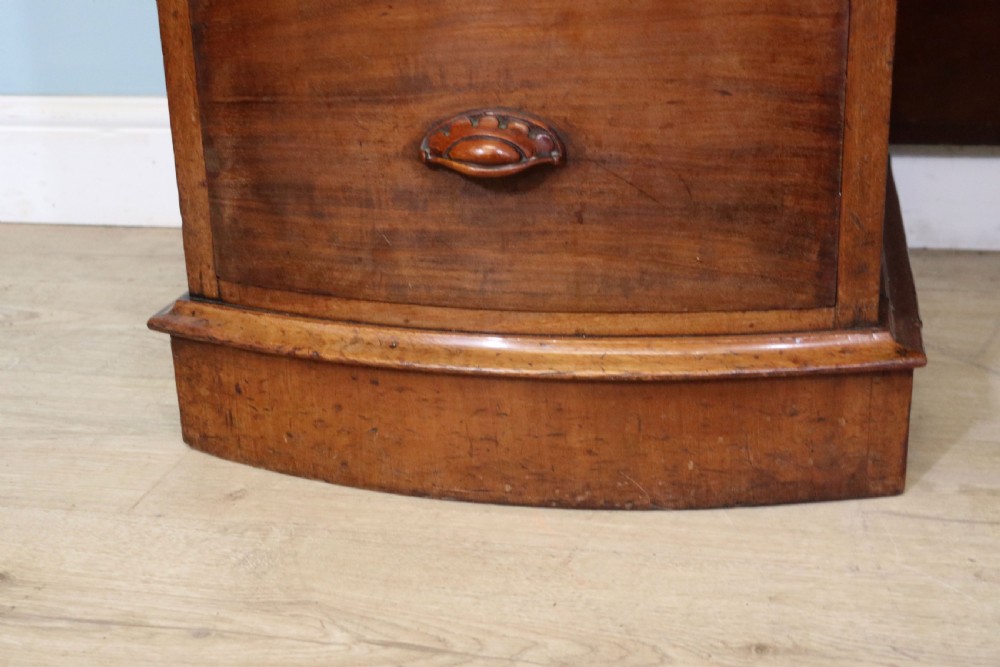 A late Victorian mahogany twin pedestal desk featuring a curved front structure and nine drawers with turned wooden handles. View XXII