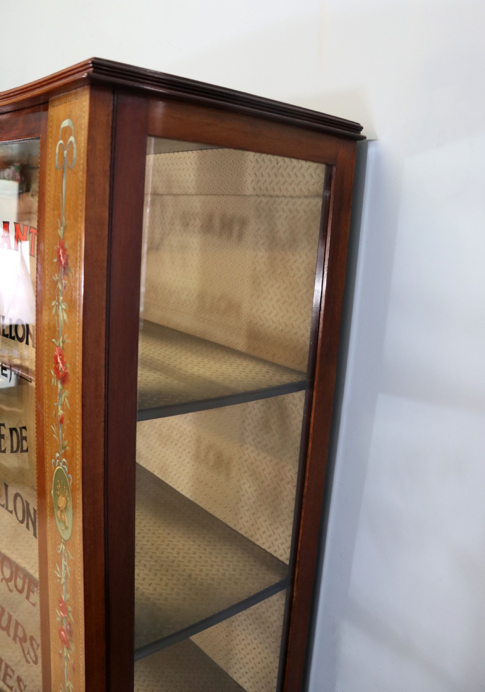 An Edwardian mahogany and satinwood display cabinet featuring curved glass doors decorated with French text and painted floral motifs, resting on slender cabriole legs. View XII