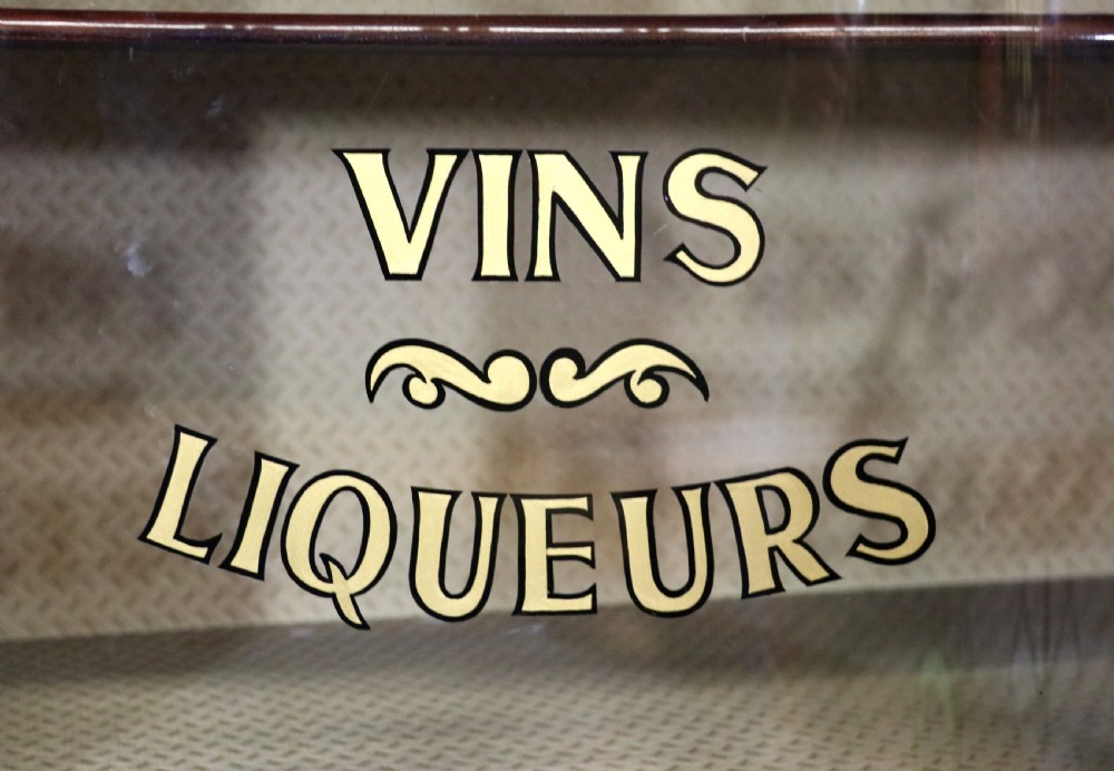 An Edwardian mahogany and satinwood display cabinet featuring curved glass doors decorated with French text and painted floral motifs, resting on slender cabriole legs. View XVI