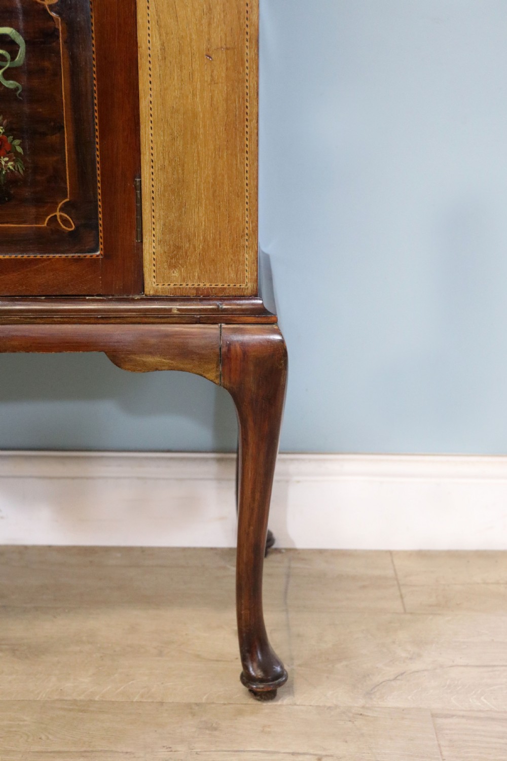 An Edwardian mahogany and satinwood display cabinet featuring curved glass doors decorated with French text and painted floral motifs, resting on slender cabriole legs. View XXIII