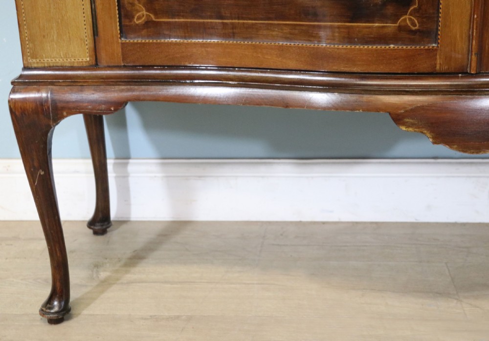 An Edwardian mahogany and satinwood display cabinet featuring curved glass doors decorated with French text and painted floral motifs, resting on slender cabriole legs. View XXIX