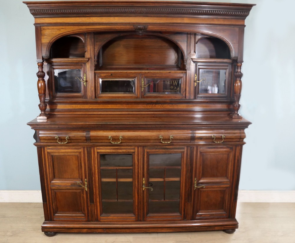 A large Victorian rosewood sideboard featuring an upper tier with arched alcoves, mirrors, and glazed cabinets over a lower base with drawers and panelled doors.