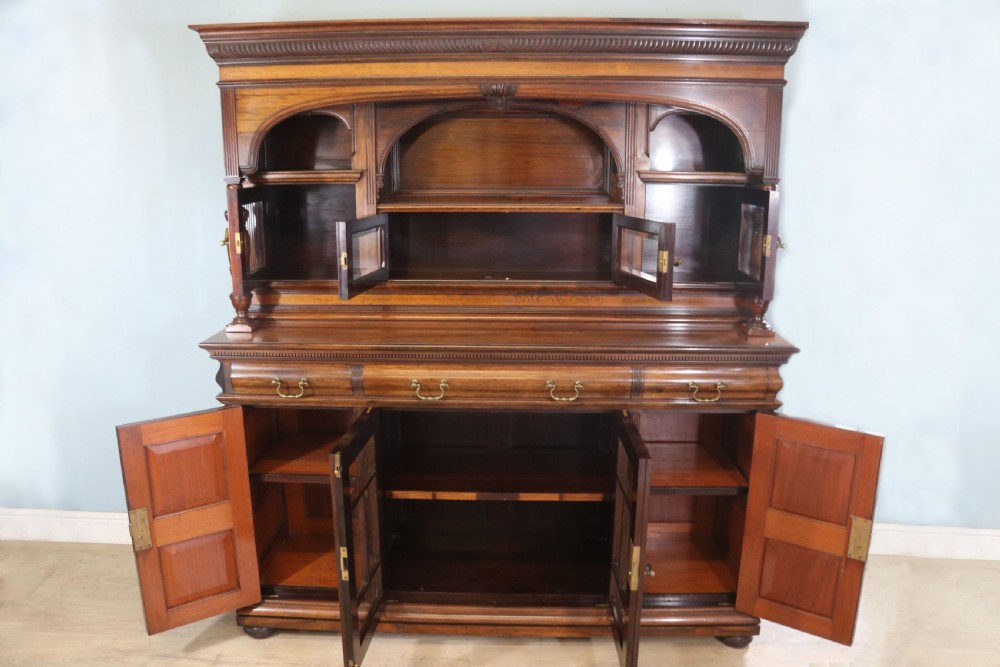 A large Victorian rosewood sideboard featuring an upper tier with arched alcoves, mirrors, and glazed cabinets over a lower base with drawers and panelled doors. View V