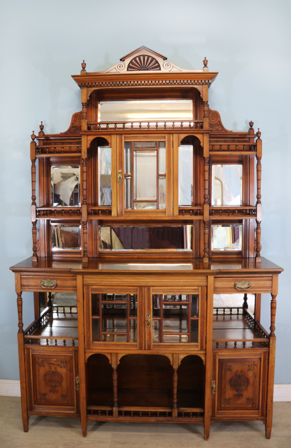 A late Victorian carved wood side cabinet featuring an ornate upper tier with multiple bevelled mirror plates, spindled galleries, glass-front doors, and carved lower cupboards.