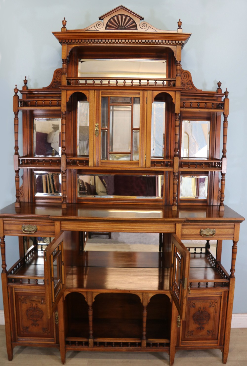 A late Victorian carved wood side cabinet featuring an ornate upper tier with multiple bevelled mirror plates, spindled galleries, glass-front doors, and carved lower cupboards. View II