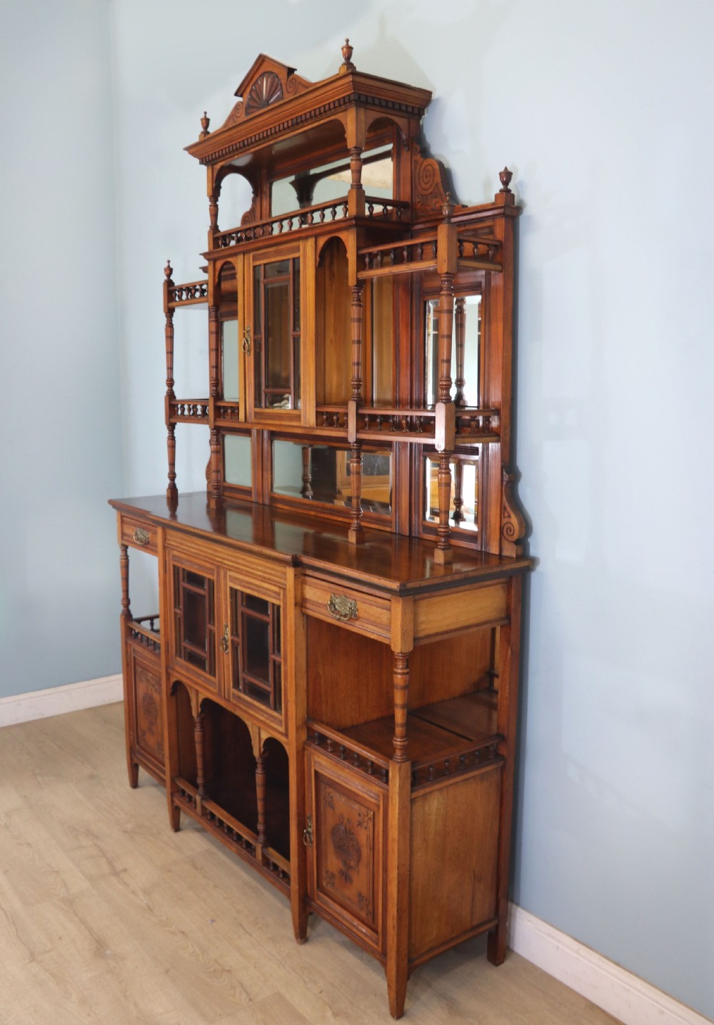 A late Victorian carved wood side cabinet featuring an ornate upper tier with multiple bevelled mirror plates, spindled galleries, glass-front doors, and carved lower cupboards. View IV