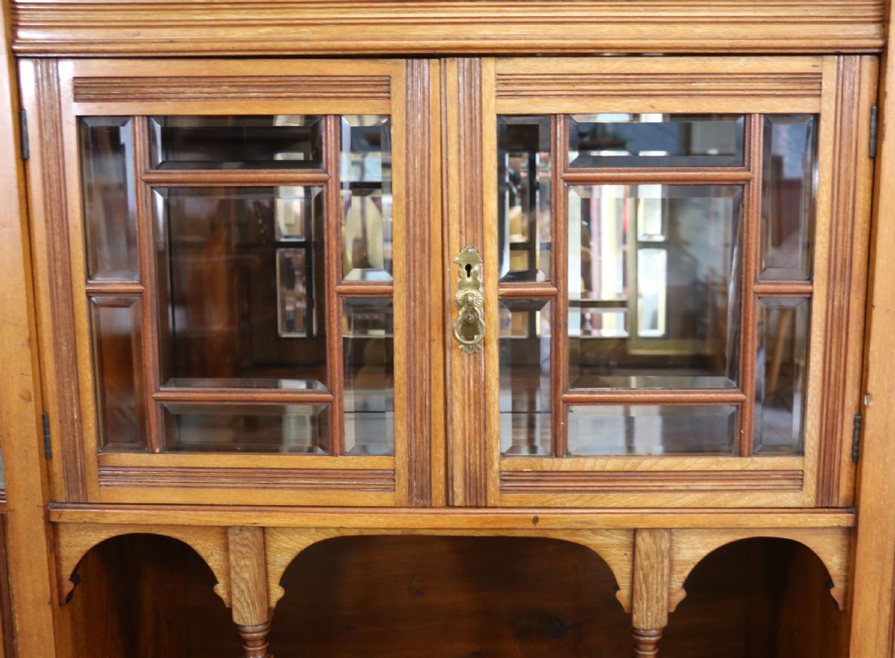 A late Victorian carved wood side cabinet featuring an ornate upper tier with multiple bevelled mirror plates, spindled galleries, glass-front doors, and carved lower cupboards. View XII