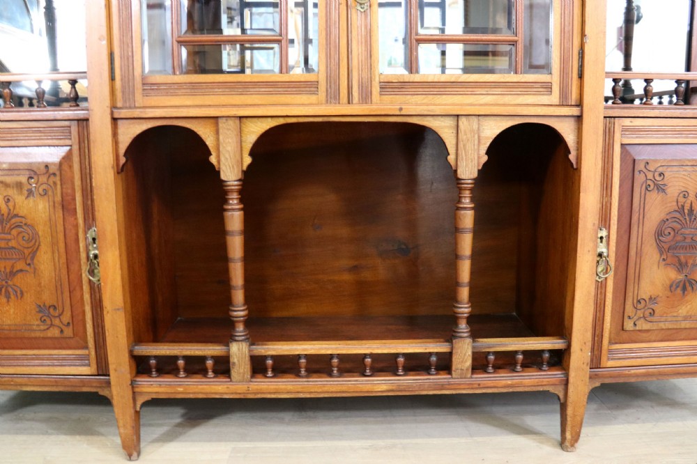 A late Victorian carved wood side cabinet featuring an ornate upper tier with multiple bevelled mirror plates, spindled galleries, glass-front doors, and carved lower cupboards. View XXIII