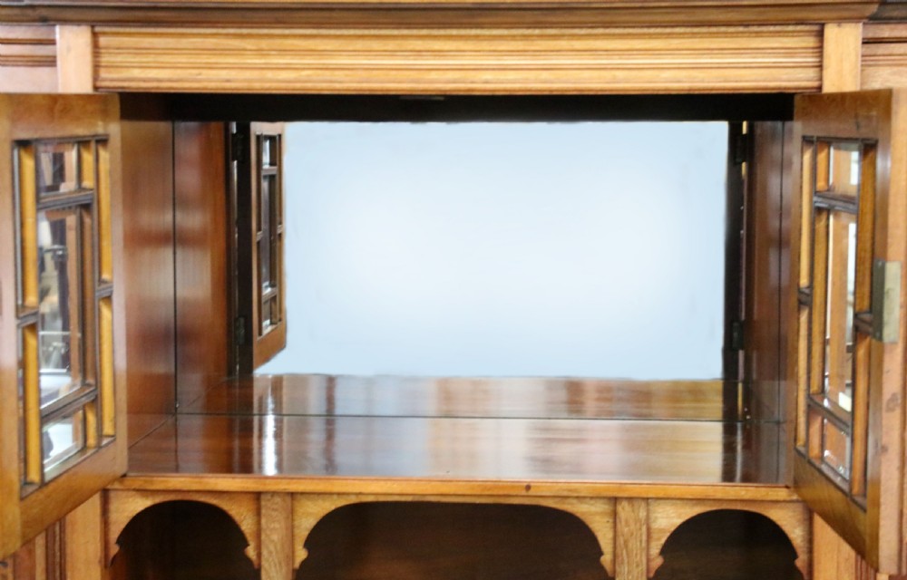A late Victorian carved wood side cabinet featuring an ornate upper tier with multiple bevelled mirror plates, spindled galleries, glass-front doors, and carved lower cupboards. View XXIV