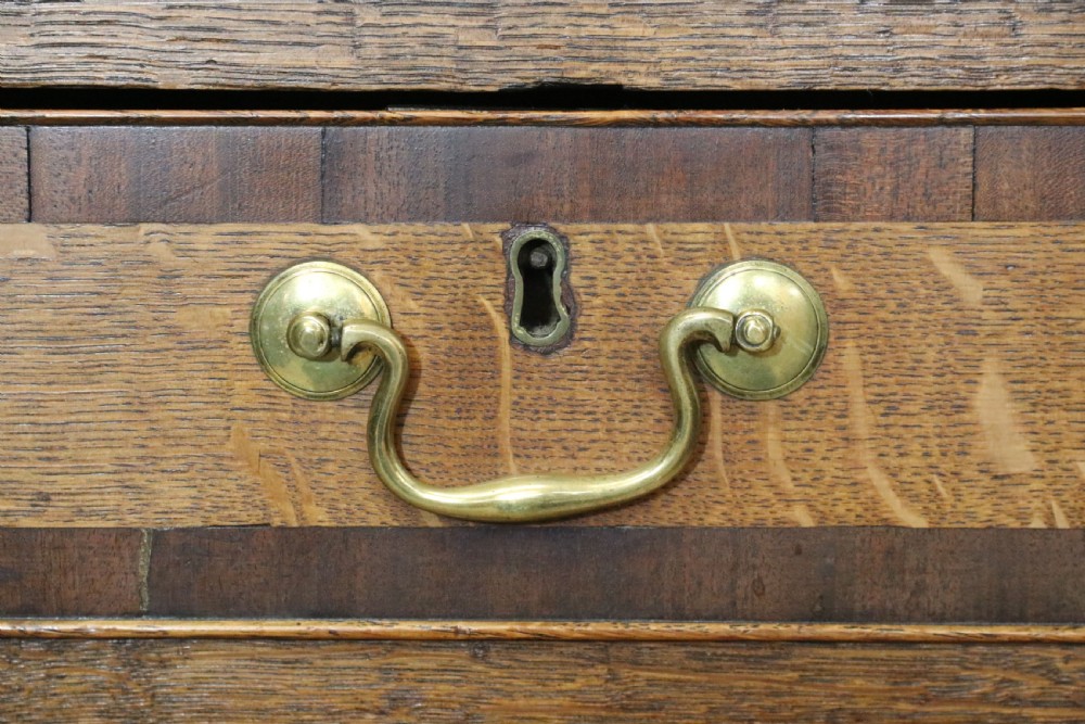 An open George III oak bureau featuring mahogany crossbanding, brass swan-neck handles, pull-out lopers, and a fitted interior with pigeonholes. View XV