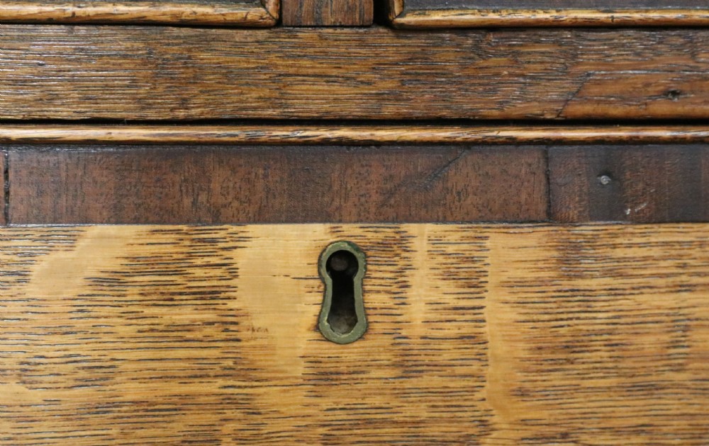 An open George III oak bureau featuring mahogany crossbanding, brass swan-neck handles, pull-out lopers, and a fitted interior with pigeonholes. View XVI