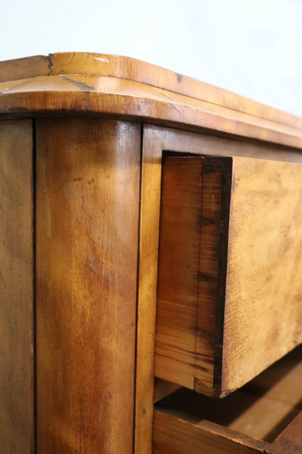 A Victorian light wood chest of drawers with two short drawers over three long drawers, featuring carved leaf handles and a solid plinth base. View VII