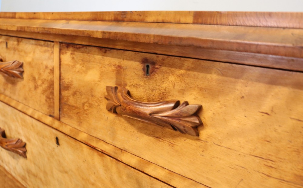 A Victorian light wood chest of drawers with two short drawers over three long drawers, featuring carved leaf handles and a solid plinth base. View IX
